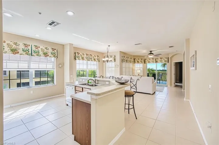 Kitchen featuring a kitchen breakfast bar, suspended lighting, open floor plan, light countertops, and light tile patterned flooring