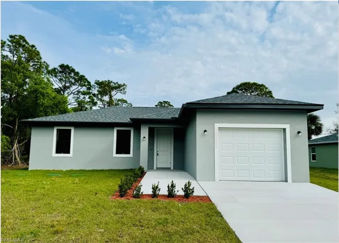 Ranch-style house with a garage, stucco siding, concrete driveway, and a front yard