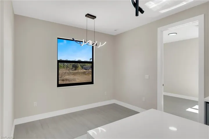 Empty room featuring baseboards and a chandelier