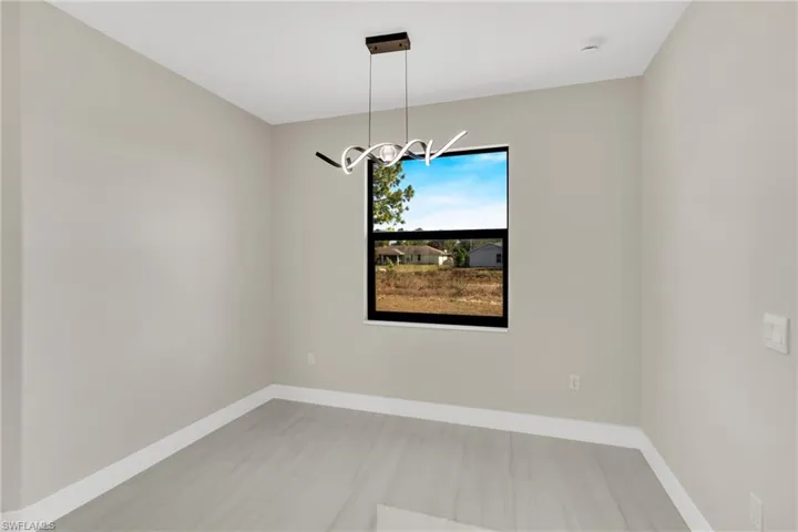 Unfurnished room with baseboards and suspended lighting