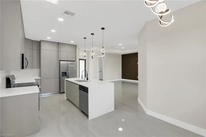 Kitchen with gray cabinetry, a center island with sink, modern cabinets, stainless steel appliances, and open floor plan