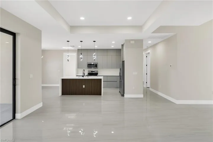 Kitchen featuring pendant lighting, open floor plan, an island with sink, and modern cabinets