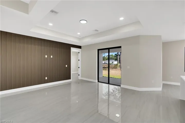 Spare room featuring wood walls, a raised ceiling, recessed lighting, and an accent wall