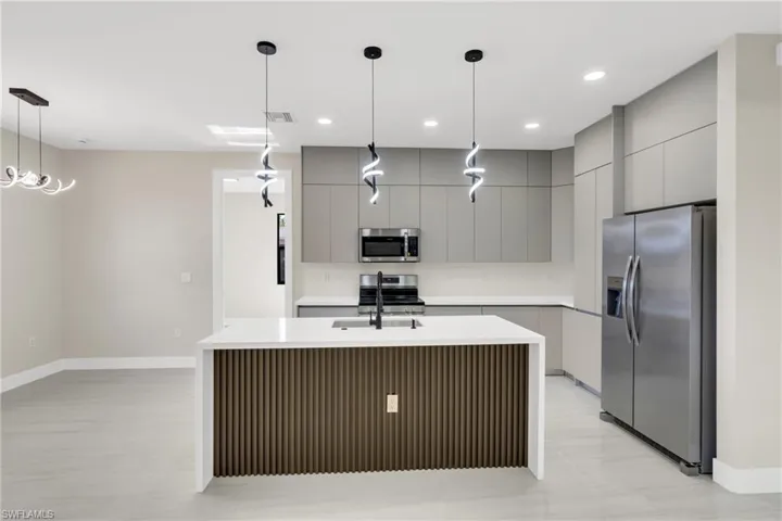 Kitchen with gray cabinetry, stainless steel appliances, pendant lighting, and modern cabinets