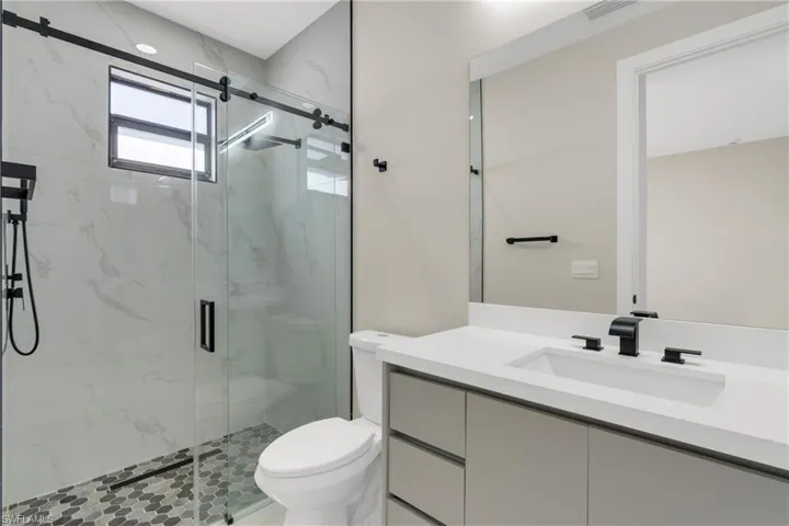 Bathroom featuring a marble finish shower and vanity