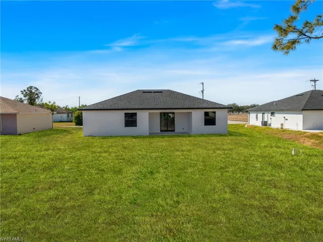 Back of property with a lawn, stucco siding, and a patio
