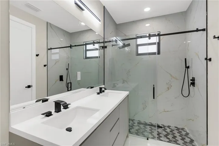Bathroom with double vanity, plenty of natural light, a marble finish shower, and recessed lighting