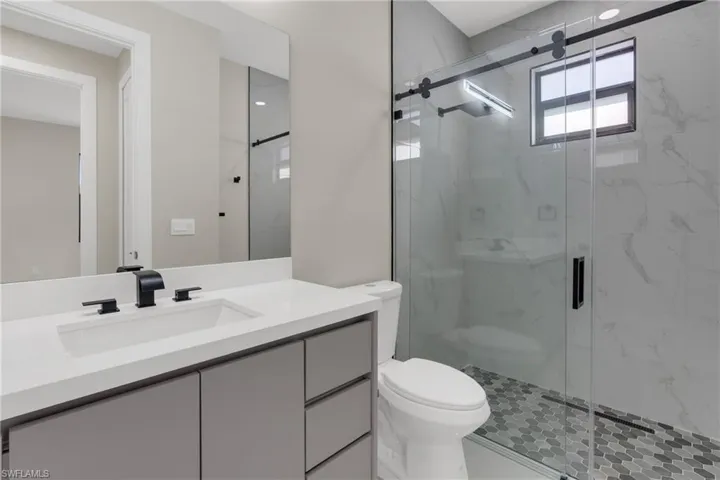 Full bath featuring a marble finish shower and vanity