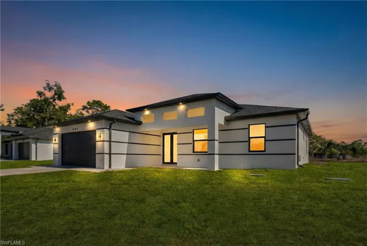 View of front facade with a front yard, stucco siding, concrete driveway, and an attached garage