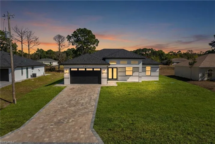 Prairie-style house with a front yard, a garage, stucco siding, and driveway