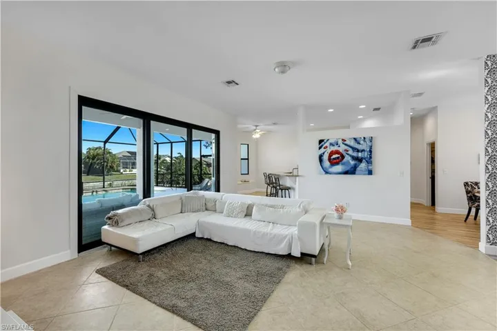 Living room featuring a sunroom, ceiling fan, light tile patterned floors, and recessed lighting