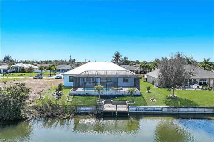 Rear view of house featuring a lanai, an outdoor pool and canal