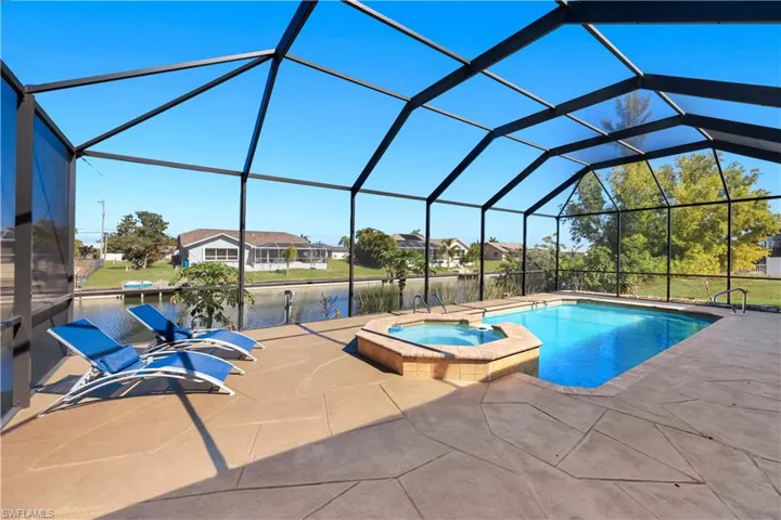 Relaxing pool / spa featuring a sunroom, a lanai, a residential view, a patio, and a water view