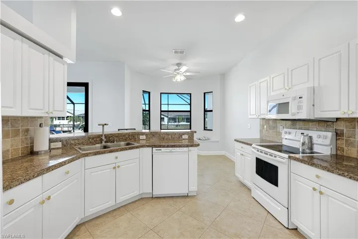 Kitchen featuring tasteful backsplash, white appliances, white cabinets, and recessed lighting