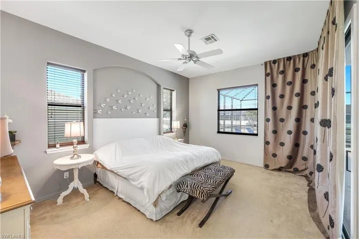Primary Bedroom with light colored carpet, multiple windows, and a ceiling fan