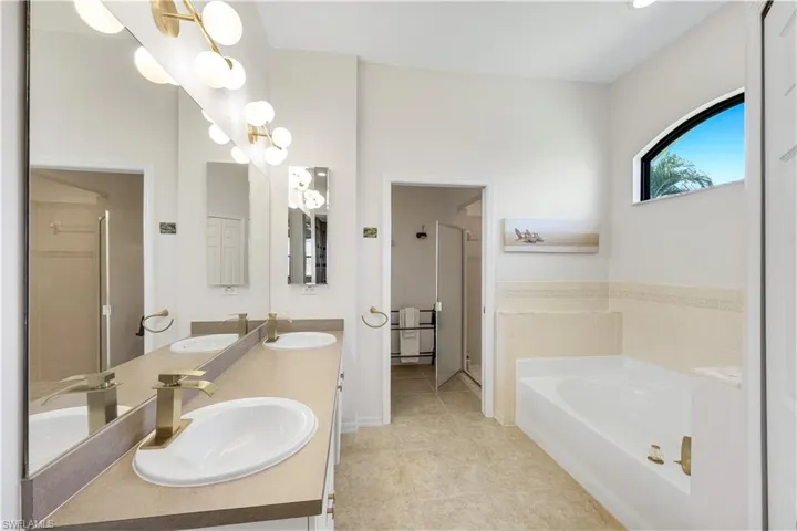 Master bath featuring a bath, double vanity, a shower stall, and light tile patterned flooring