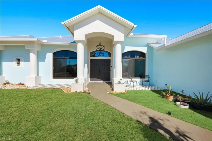 View of exterior entry featuring a yard and stucco siding