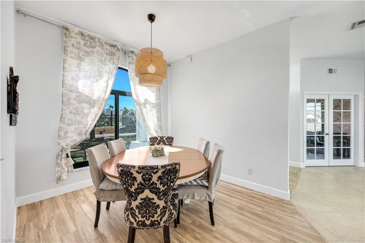Dining room with french doors, light wood-style flooring, and vaulted ceiling