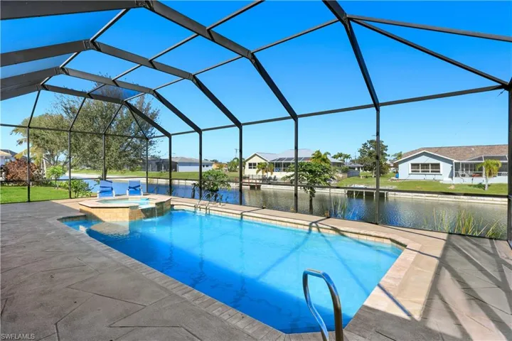 Integrated pool / hot tub with a lanai, a water view, a residential view, and a sunroom