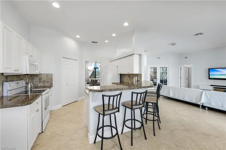 Kitchen with white appliances, tasteful backsplash, dark countertops, and recessed lighting