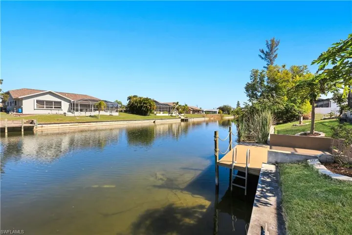 Dock area with a water view and a lawn