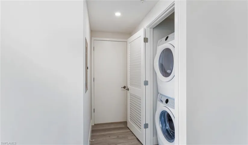 Washroom with light wood-type flooring and stacked washer and clothes dryer