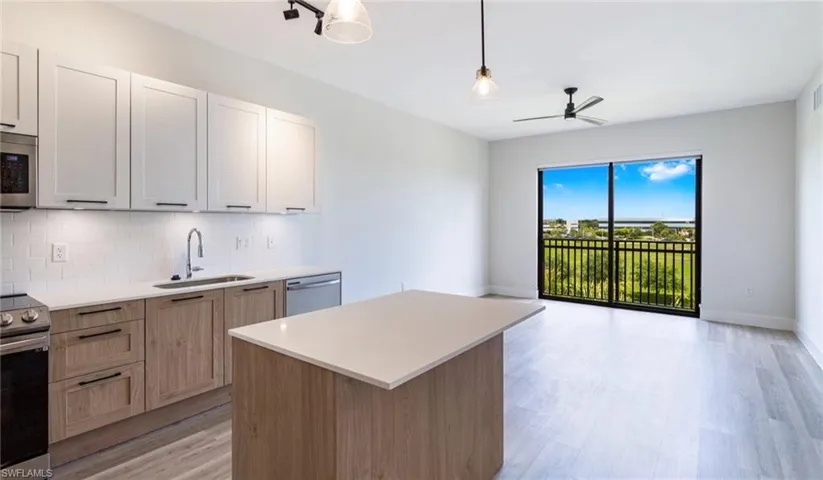 Kitchen with appliances with stainless steel finishes, decorative backsplash, light wood-type flooring, white cabinetry, and pendant lighting