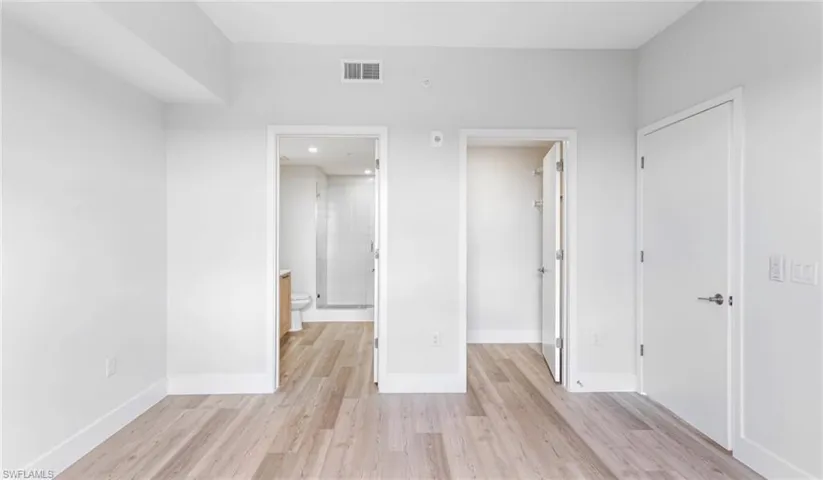 Unfurnished bedroom with a walk in closet, light wood finished floors, and connected bathroom
