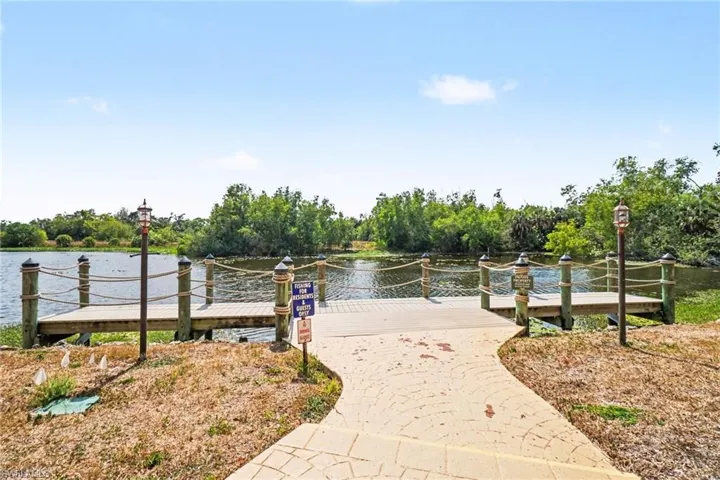 View of home's community with a water view, view of wooded area, and a dock