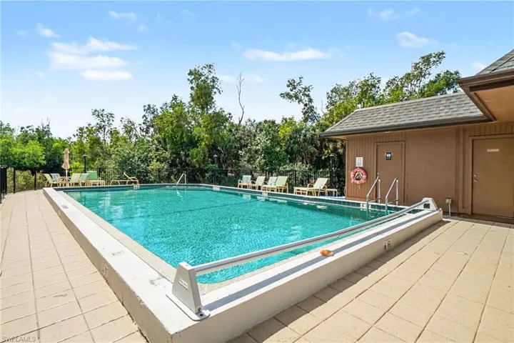 Community pool with a patio area and view of scattered trees