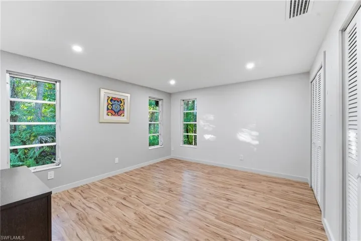 Unfurnished bedroom with light wood-type flooring, recessed lighting, and multiple closets