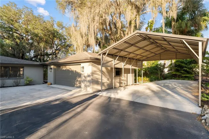 View of front of property featuring stucco siding, a shingled roof, driveway, and a carport