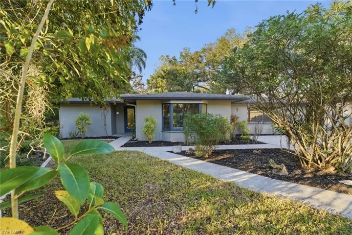 View of front of property with stucco siding, a front yard, and a garage