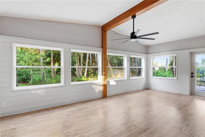 Unfurnished sunroom featuring wood finished floors, vaulted ceiling with beams, and wood walls