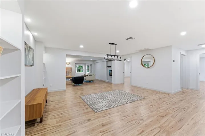 Workout room with light wood-style flooring, recessed lighting, and a glass covered fireplace