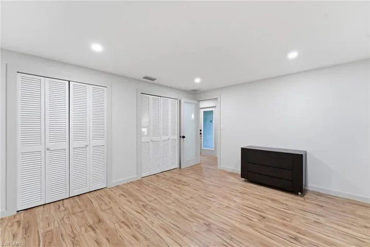 Unfurnished bedroom with two closets, light wood-style flooring, and recessed lighting