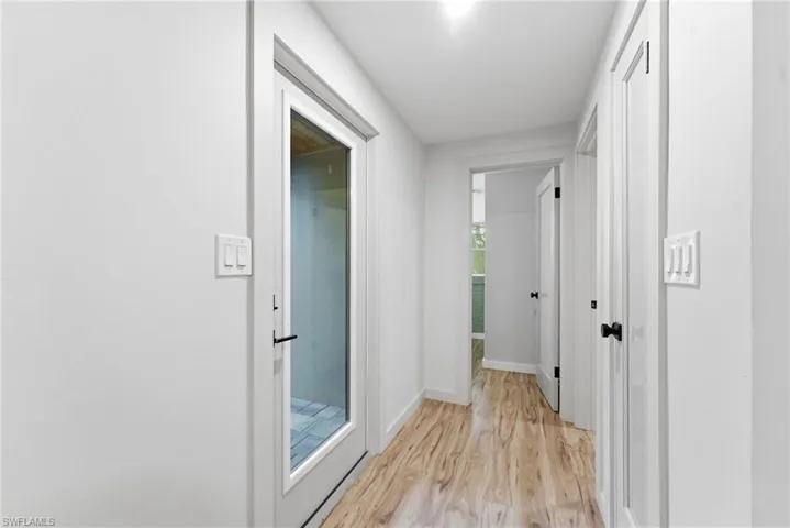 Corridor with light wood-style flooring and baseboards