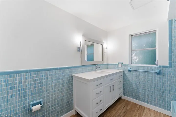 Bathroom with vanity, wainscoting, tile walls, and light wood-type flooring