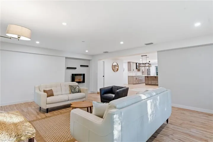 Living area with light wood-type flooring, a glass covered fireplace, and recessed lighting