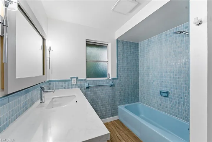 Bathroom with tile walls, vanity,  shower combination, wainscoting, and light wood finished floors