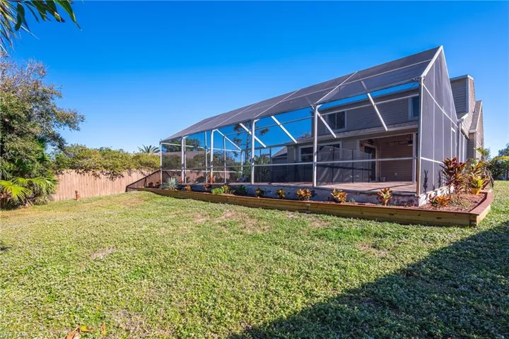 Rear view of property featuring a lawn and glass enclosure
