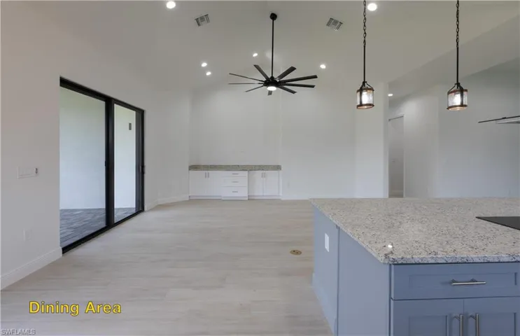 Kitchen featuring stainless steel fridge, decorative light fixtures, light hardwood / wood-style flooring, a center island, and ceiling fan