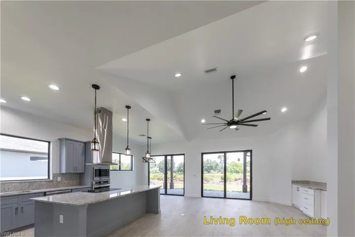 Kitchen featuring light stone counters, ceiling fan, extractor fan, pendant lighting, and a kitchen island
