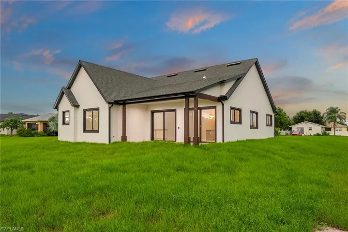 Property exterior at dusk featuring a lawn