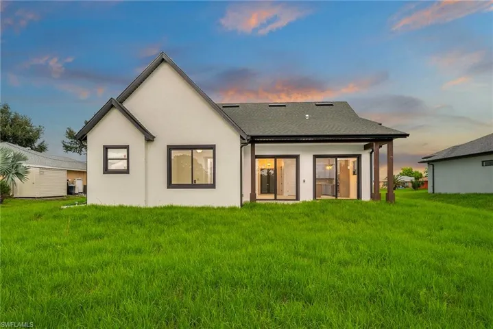 Back house at dusk featuring a lawn
