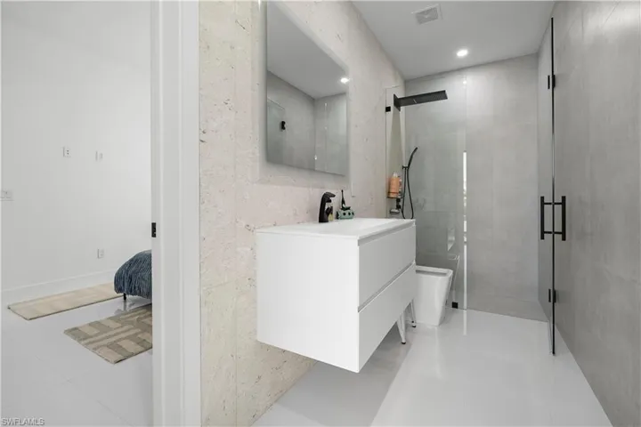 Full bathroom featuring vanity, a stall shower, tile walls, and light tile patterned floors