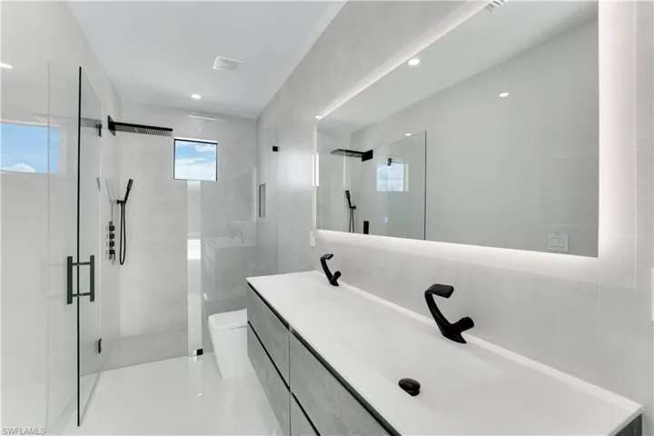 Bathroom with toilet, a stall shower, visible vents, tile patterned flooring, and vanity
