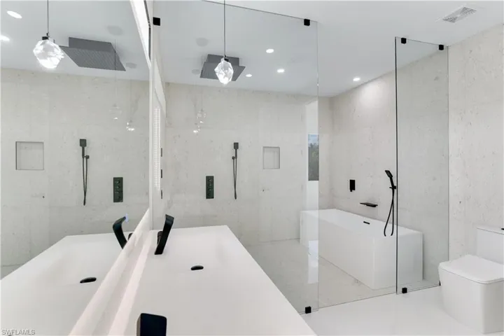 Bathroom with toilet, tile walls, visible vents, a freestanding tub, and vanity