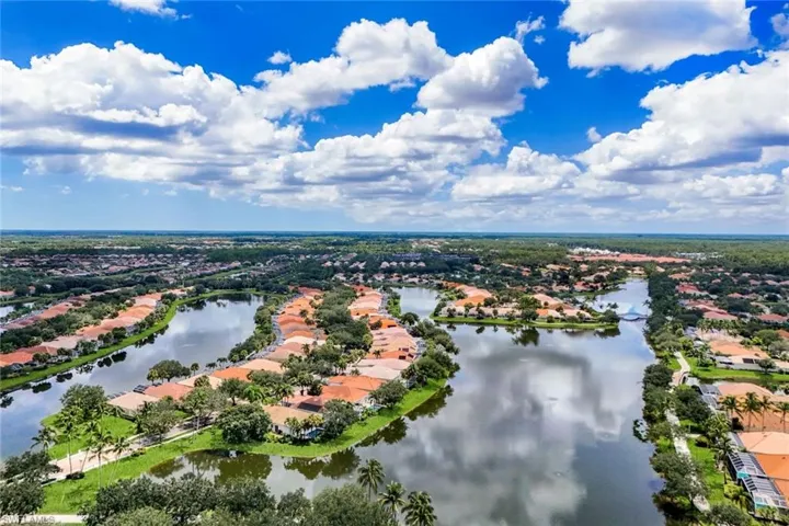 Expansive community featuring multiple waterways, numerous residential properties with terra cotta roofs, and abundant mature trees