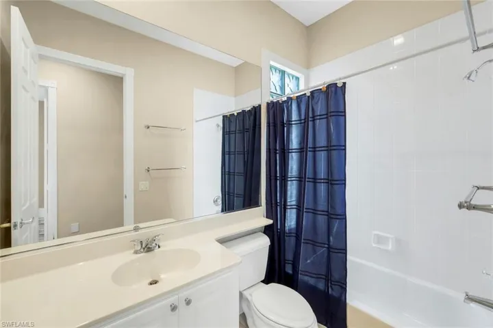 Built-in vanity with integrated sink, expansive wall-mounted mirror, and tile-surround bathtub